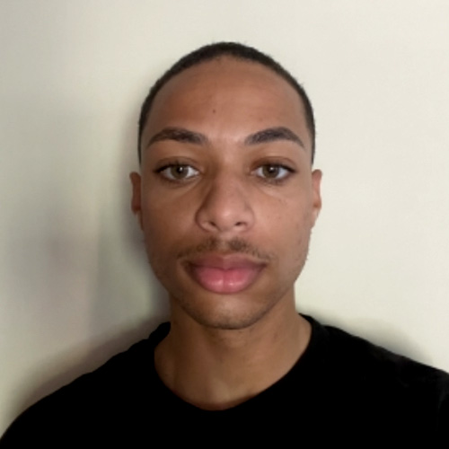 Headshot of UCR student, Raymon Prothro wearing a black shirt and standing against a light beige background